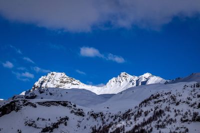 Scenic view of snow covered mountains against blue sky