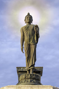 Low angle view of buddha statue against sky