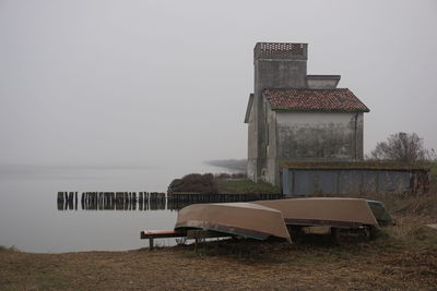 Empty chair on table by sea against sky