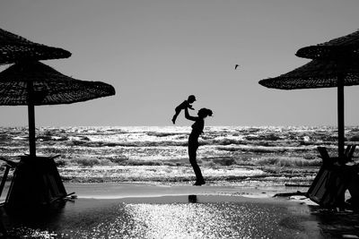 Silhouette people on beach against clear sky