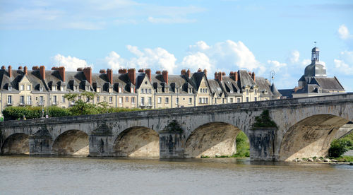 Arch bridge over river against buildings
