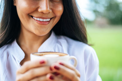 Close-up portrait of a woman holding coffee cup