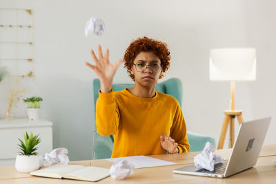 Portrait of young woman using mobile phone while sitting on table