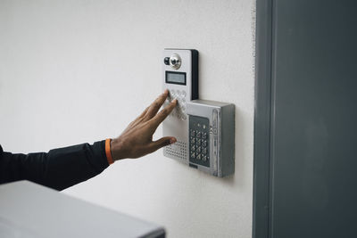 Cropped image of delivery man ringing intercom on wall