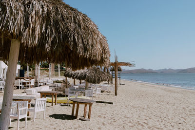 Chairs on beach against clear sky