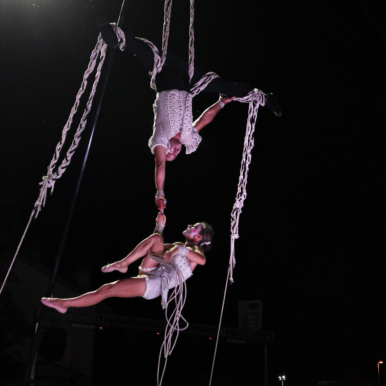 LOW ANGLE VIEW OF WOMAN CLIMBING HANGING ON ROPE