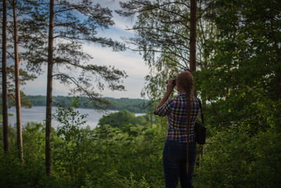 Rear view of person standing by trees in forest