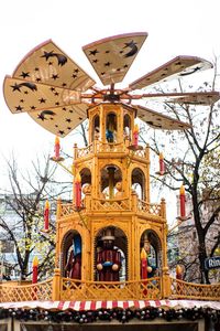 Low angle view of ferris wheel by building against sky