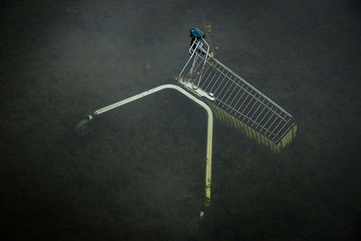 High angle view of shopping cart fallen in pond