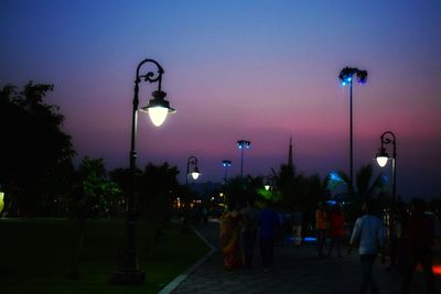 People walking on illuminated street lights in city at night