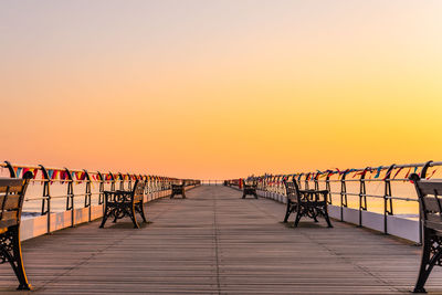 Pier over sea against clear sky during sunset