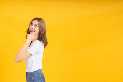 Portrait of a smiling young woman against yellow background