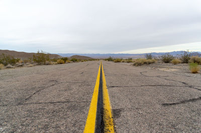 Diminishing perspective road against cloudy sky