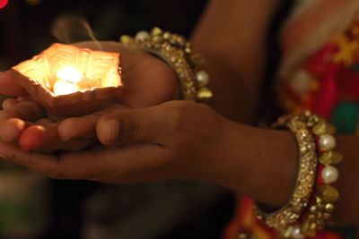 Midsection of woman holding lit diya