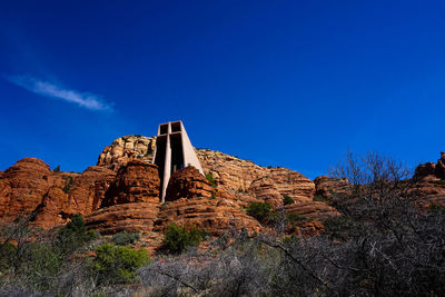 Low angle view of rocks on mountain against blue sky