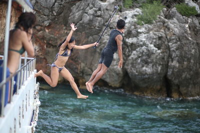 People on rock formation in water