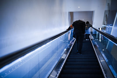 Rear view of man walking on escalator