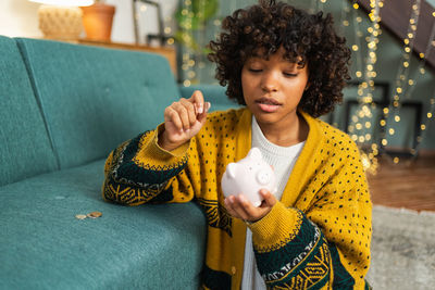 Young woman using mobile phone while sitting on sofa at home