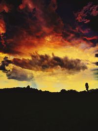 Silhouette landscape against dramatic sky during sunset