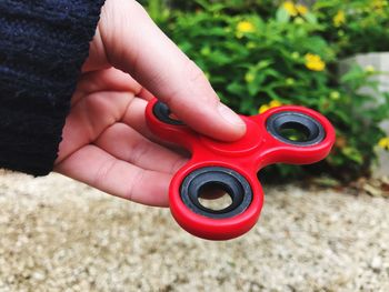 Cropped hand holding red fidget spinner