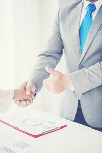 Midsection of man holding hands on table