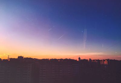 Silhouette cityscape against sky at sunset