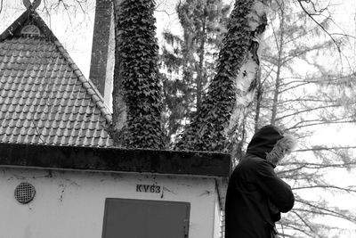 Low angle view of tree against built structure in winter