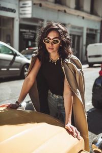 Young woman standing by car in city