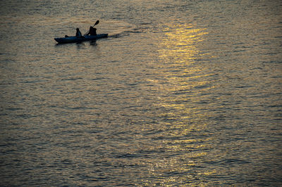 Silhouette man in boat sailing on sea