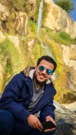 Portrait of young man wearing sunglasses sitting outdoors