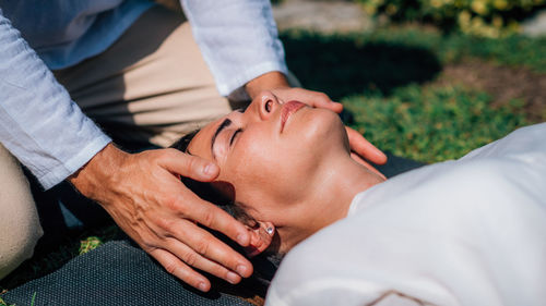 Woman in reiki spiritual healing session. reiki therapist holding hands above heart chakra 