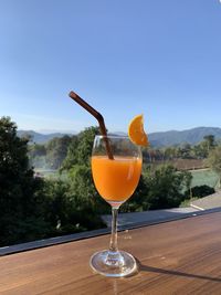 Close-up of wineglass on table against orange sky