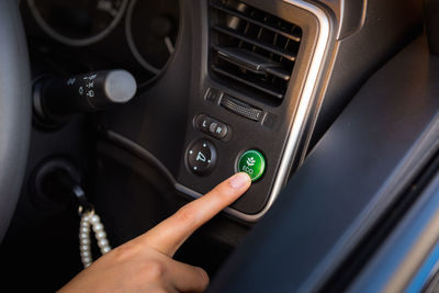 Close-up of hand pressing button in car