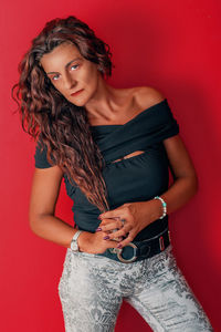 Portrait of woman with long curly brown hair against red background