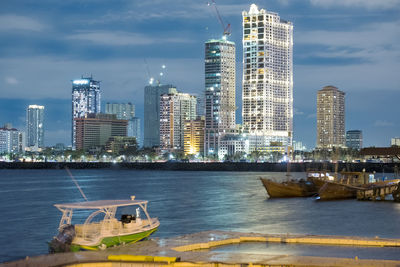 Boats in sea against modern buildings in city