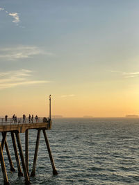 Pier over sea against sky during sunset