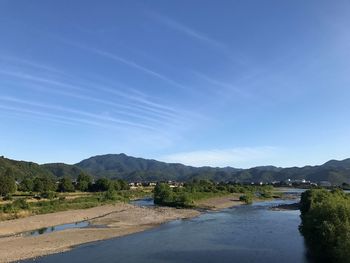 Scenic view of road by mountains against blue sky