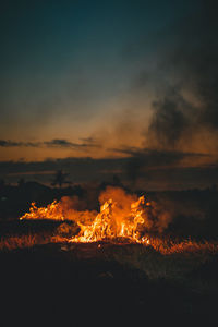 Silhouette of bonfire against sky at sunset