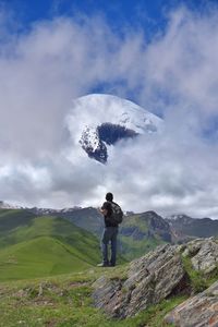 Rear view of man standing on mountain against sky