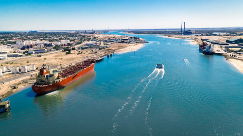 High angle view of harbor and cityscape against blue sky