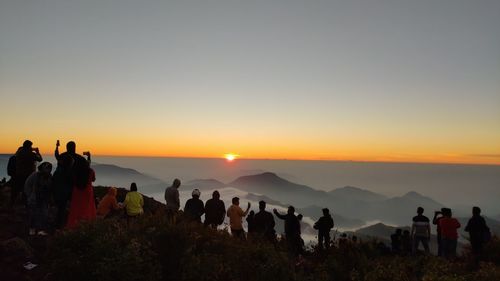 People on mountain against sky during sunset