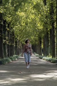 Full length of woman walking on road along trees