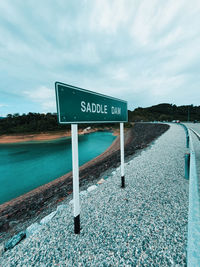 Information sign by road against sky