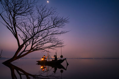 Silhouette tree by sea against sky at sunset