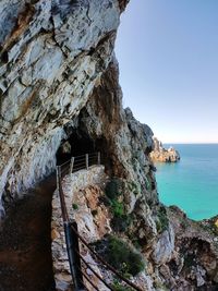 Rock formation by sea against sky