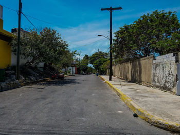 Road amidst trees and buildings against sky