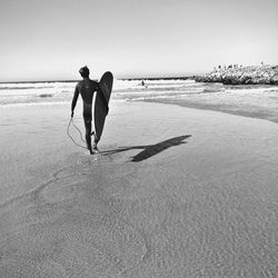 Full length of men on beach against clear sky