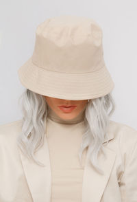Close-up of woman wearing hat against white background