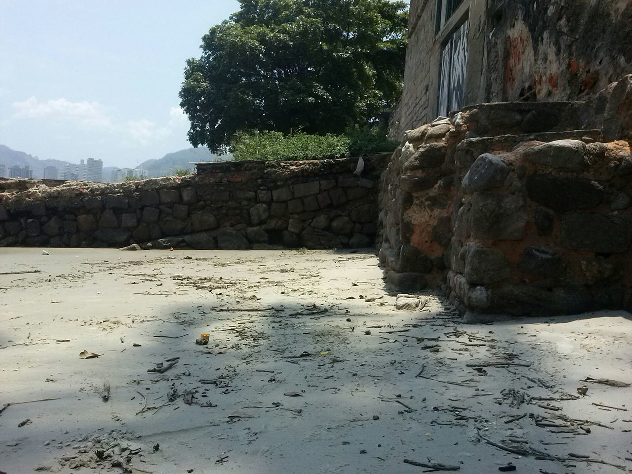 architecture, built structure, building exterior, water, tree, rock - object, house, sky, day, river, outdoors, waterfront, stone wall, sunlight, reflection, wall - building feature, no people, stone - object, nature, residential structure