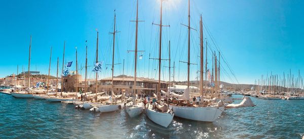 Sailboats moored at harbor against blue sky